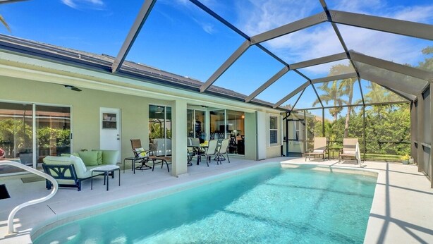 A covered swimming pool with lounge chairs and a patio area.