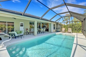 A covered swimming pool with lounge chairs and a patio area.