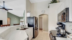 A modern kitchen with a central island, stainless steel appliances, and a clock on the wall.
