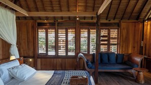 A wooden room with a bed, a sofa, and a window with blinds. - 4 bedroom Rote Beach House (Rote Barat)