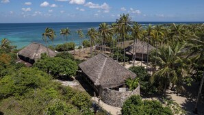 A tropical resort with thatched-roof huts, palm trees, and a view of the ocean. - 4 bedroom Rote Beach House (Rote Barat)