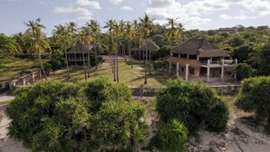 A tropical resort with thatched-roof huts, palm trees, and a clear sky. - 4 bedroom Rote Beach House (Rote Barat)