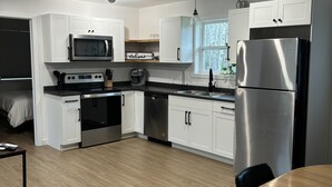 A modern kitchen with white cabinets, stainless steel appliances, and a wooden dining table.