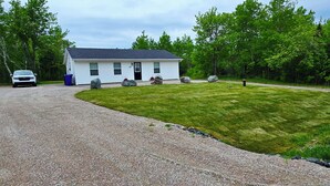 A single-story house with a gravel driveway and a well-maintained lawn.