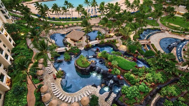 A resort with multiple swimming pools, palm trees, and a beach.
