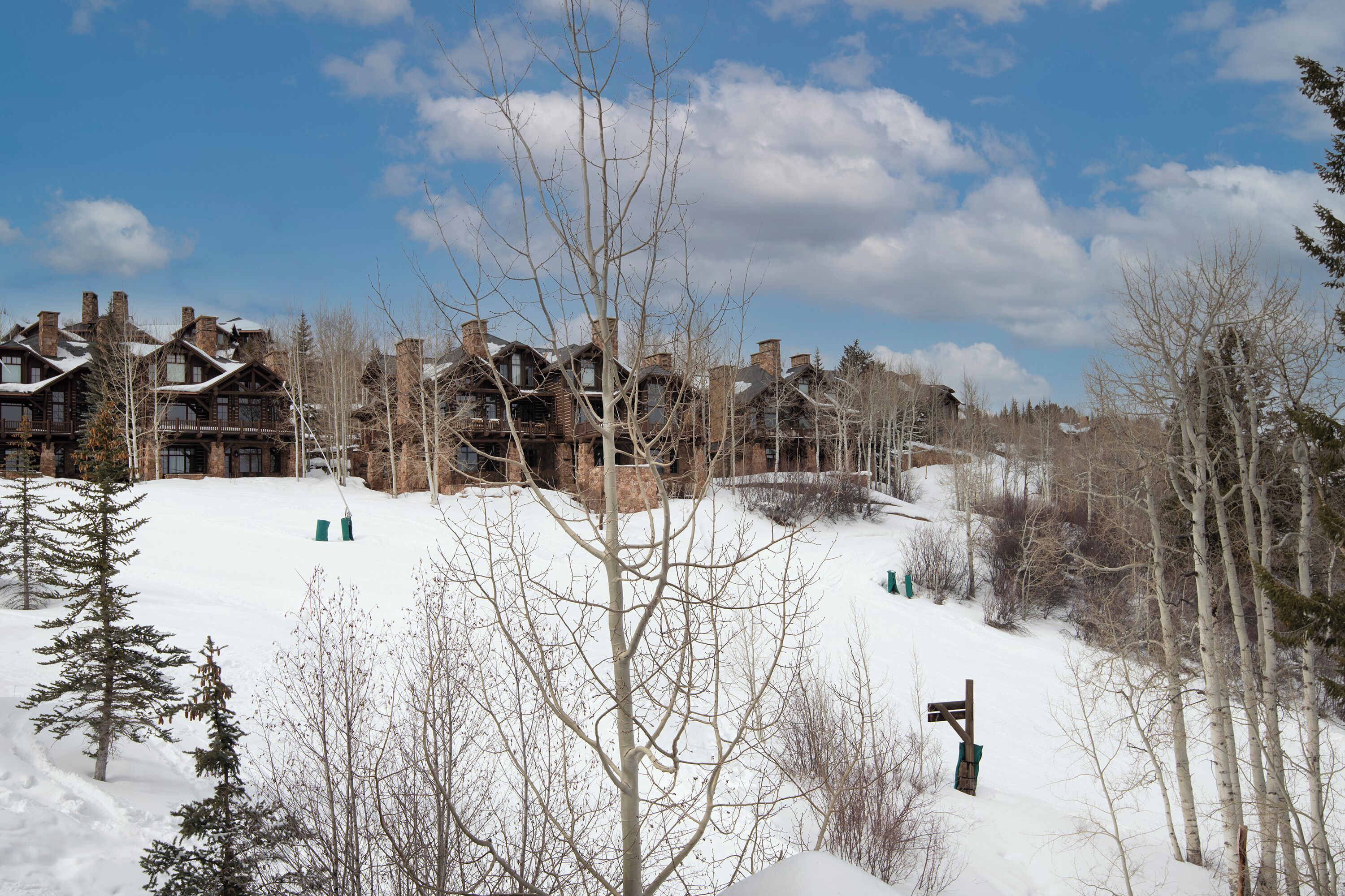 A snow-covered landscape with a large lodge featuring multiple chimneys and a wooden facade.