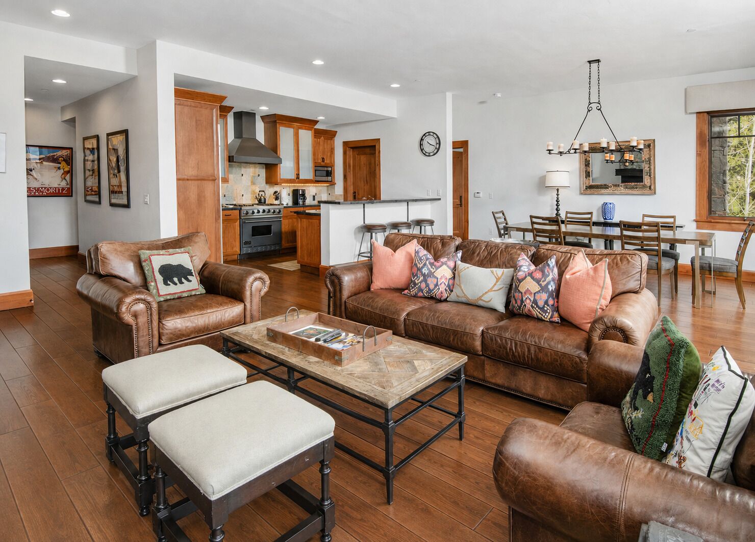A spacious living room with leather sofas, a coffee table, and a dining area with wooden chairs and a chandelier.