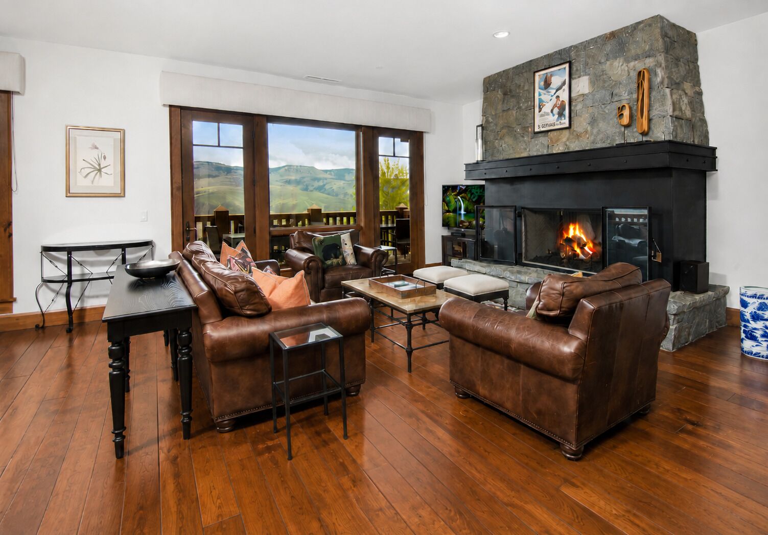Una sala de estar con sofás de cuero, una chimenea y vistas al exterior.