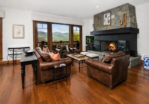 Ein Wohnzimmer mit Ledersofas, einem Kamin und Blick ins Freie.