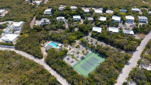 An aerial view of a residential area with multiple houses, a tennis court, and a swimming pool.