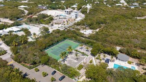 An aerial view of a residential area with a tennis court, a swimming pool, and several houses.
