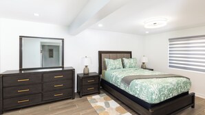 A bedroom with a bed, nightstands, a dresser, and a mirror.