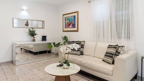 A living room with a sofa, a coffee table, a desk, and a large mirror.