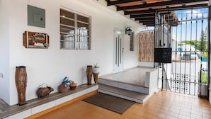 A spacious entrance with a tiled floor, a wooden bench, decorative vases, and a welcome sign.