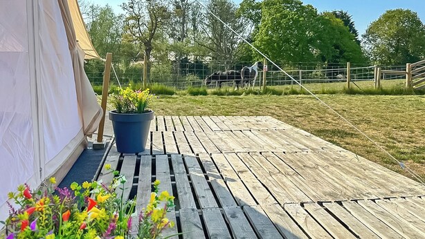 Eine Holzterrasse mit einem Zelt und Topfpflanzen.