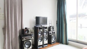 A room with a large window, a television on a stand, and a speaker system.