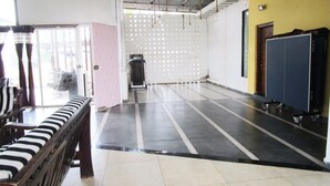 A spacious room with a large window, a bench, a treadmill, and a wall with circular holes.