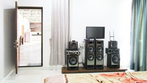 A bedroom with a bed, a TV, and a speaker system.