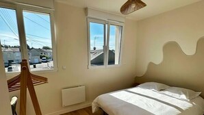 Una camera da letto con un letto, una finestra, un termosifone e una scala in legno.