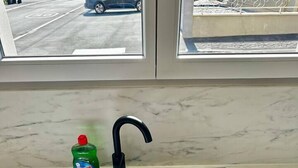 Lavello da cucina con una bottiglia di detersivo, una spugna e un panno.