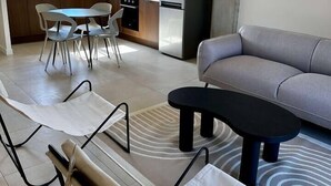 Un soggiorno moderno con un divano grigio, un tavolino da caffè nero e un'area pranzo con un tavolo rotondo e sedie bianche.