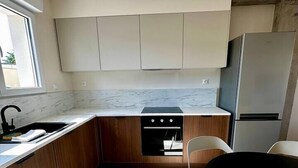 Una cucina moderna con mobili in legno, forno integrato, frigorifero e zona pranzo con tavolo e sedie.