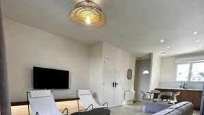 A modern living room with a sofa, a TV, and a dining area.