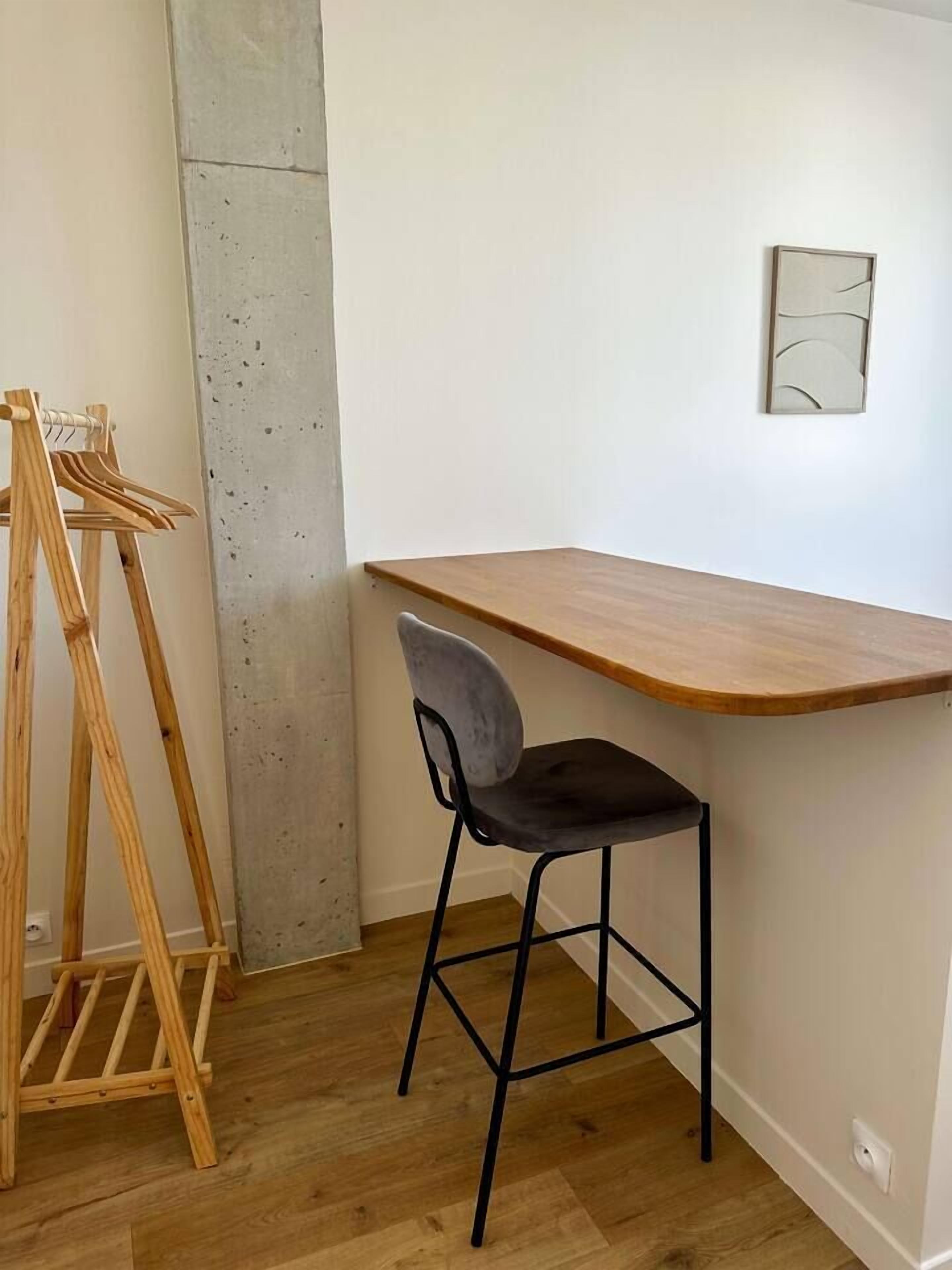 A corner room with a wooden desk and a black chair.