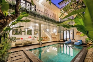 Zona de piscina con escalera, asientos y plantas.