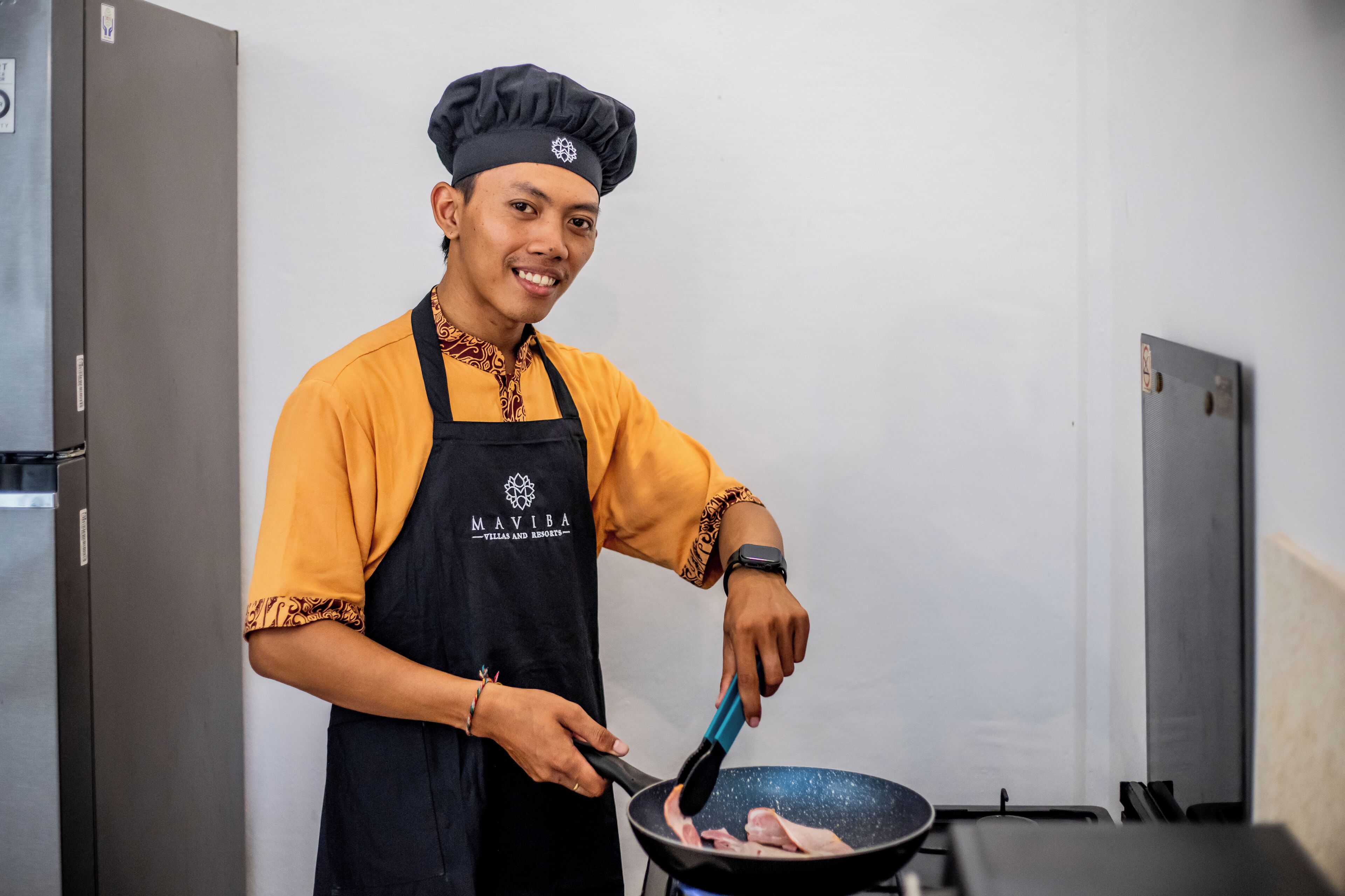 A person in a chef's uniform cooking in a kitchen.