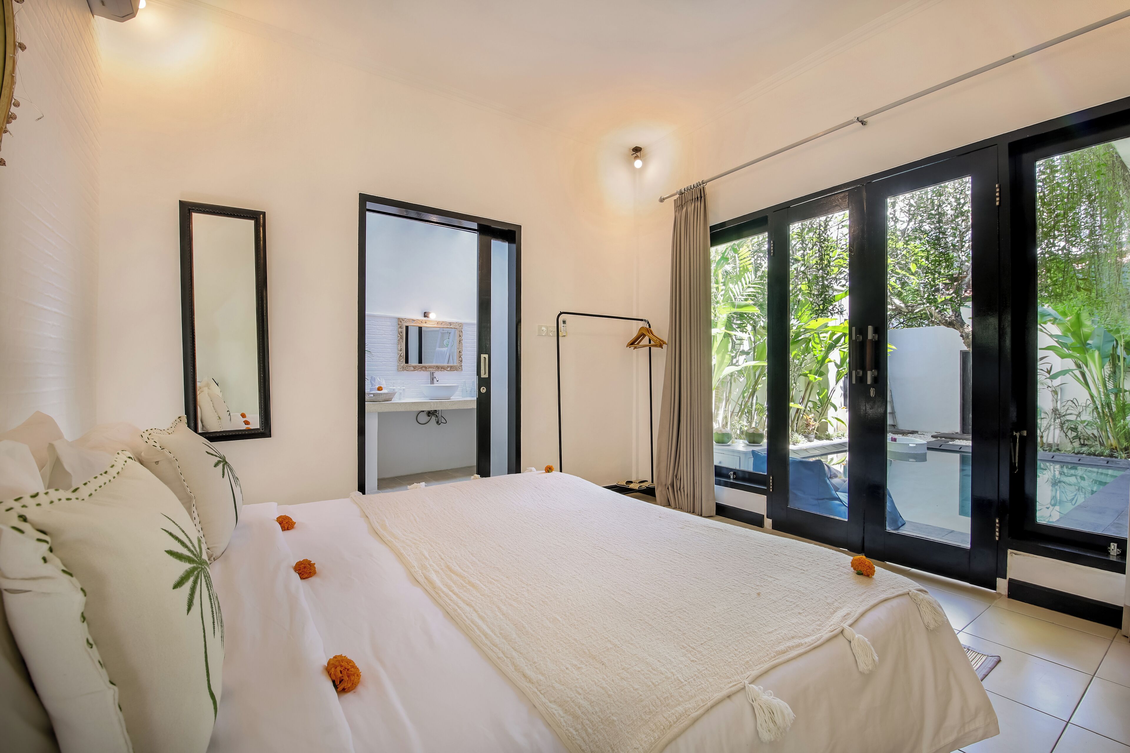 Una camera d'albergo con un letto grande, uno specchio, un comodino e vista sull'esterno.