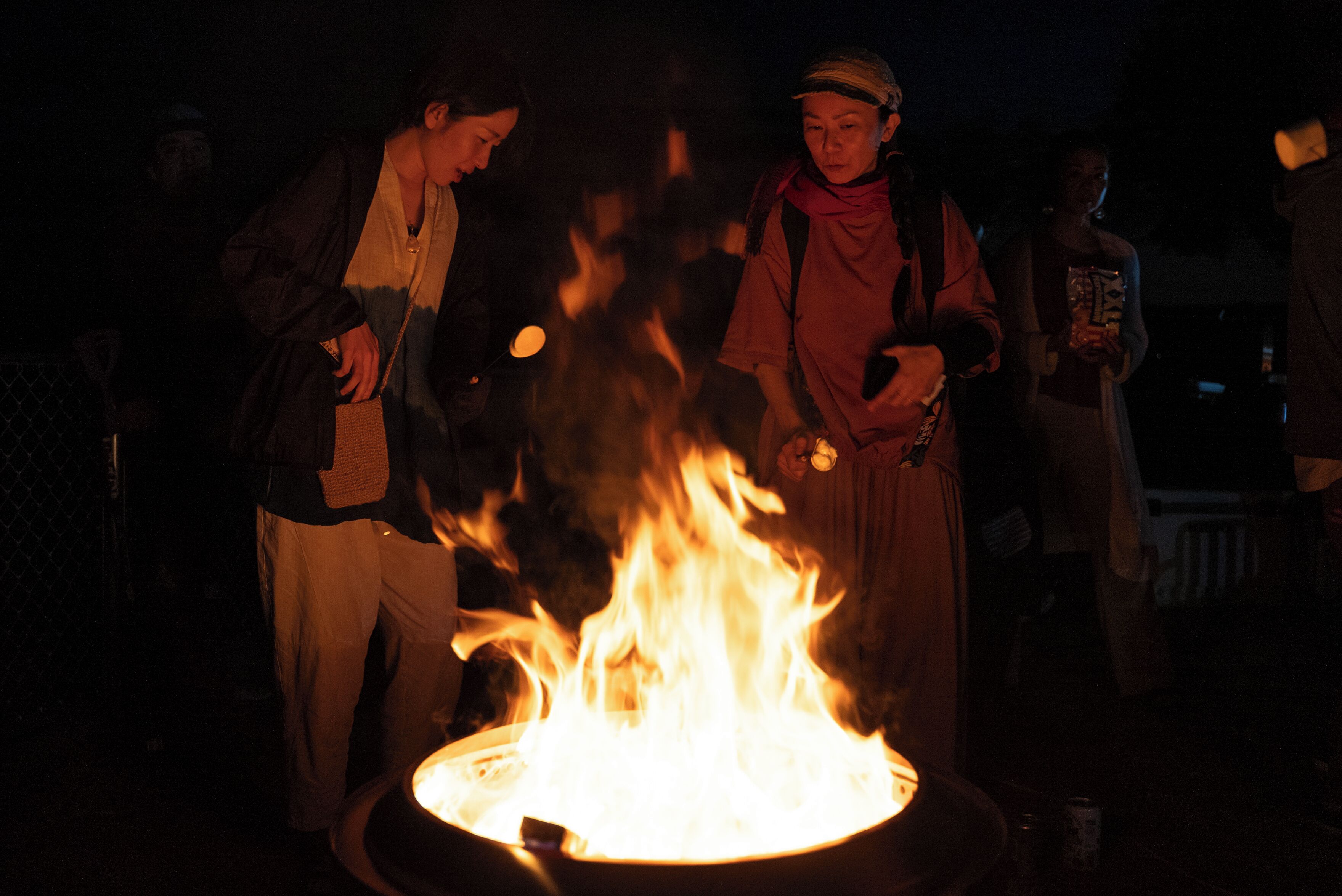 A group of people gathered around a campfire at night.