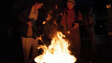 A group of people gathered around a campfire at night.