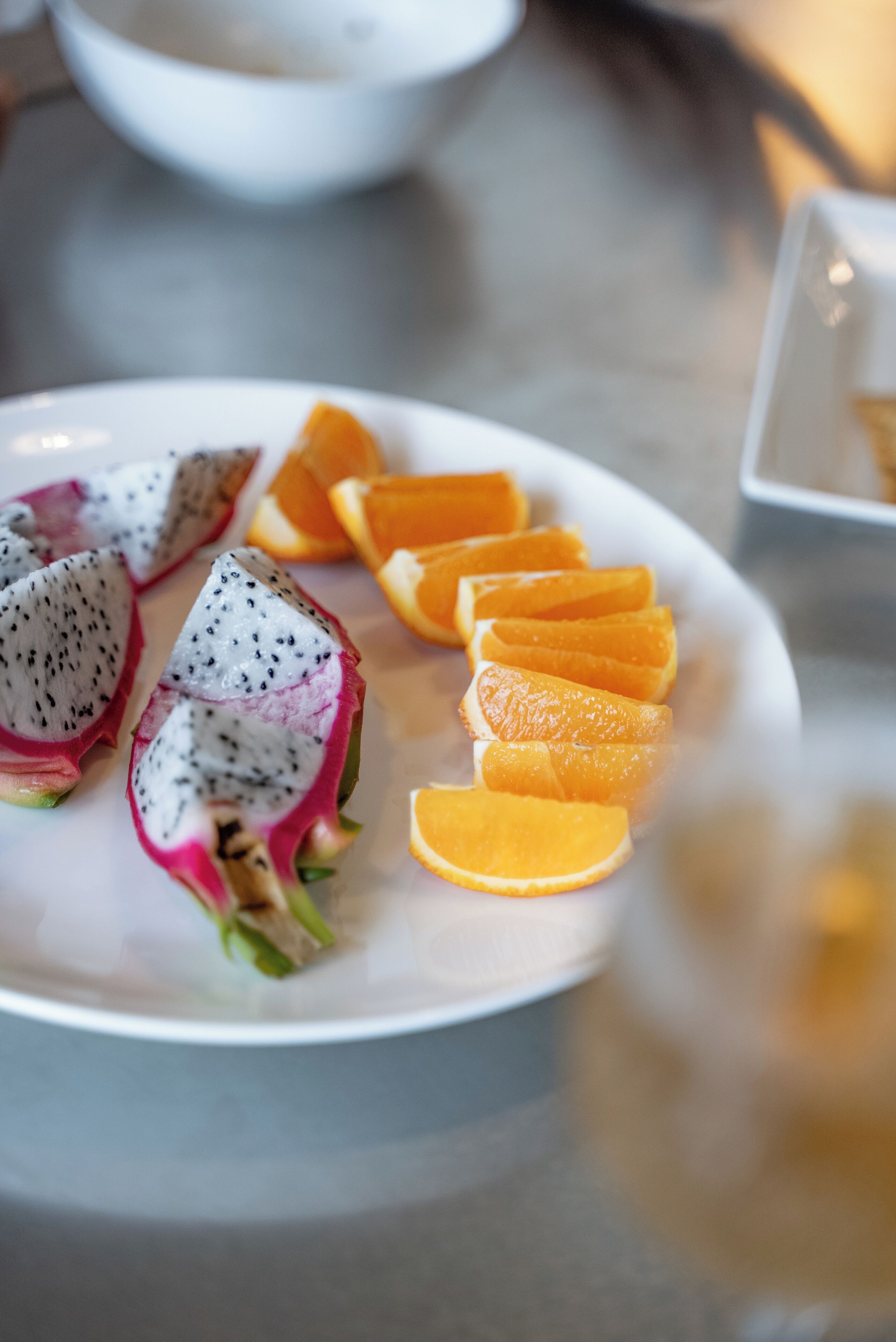 A plate with sliced dragon fruit and oranges.