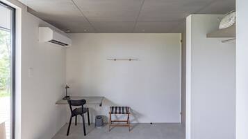 A minimalist room with a desk, chair, and a small bench.