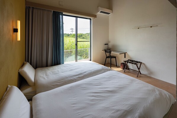A room with two beds, a desk, and a chair. - Dei Amami (Amami)