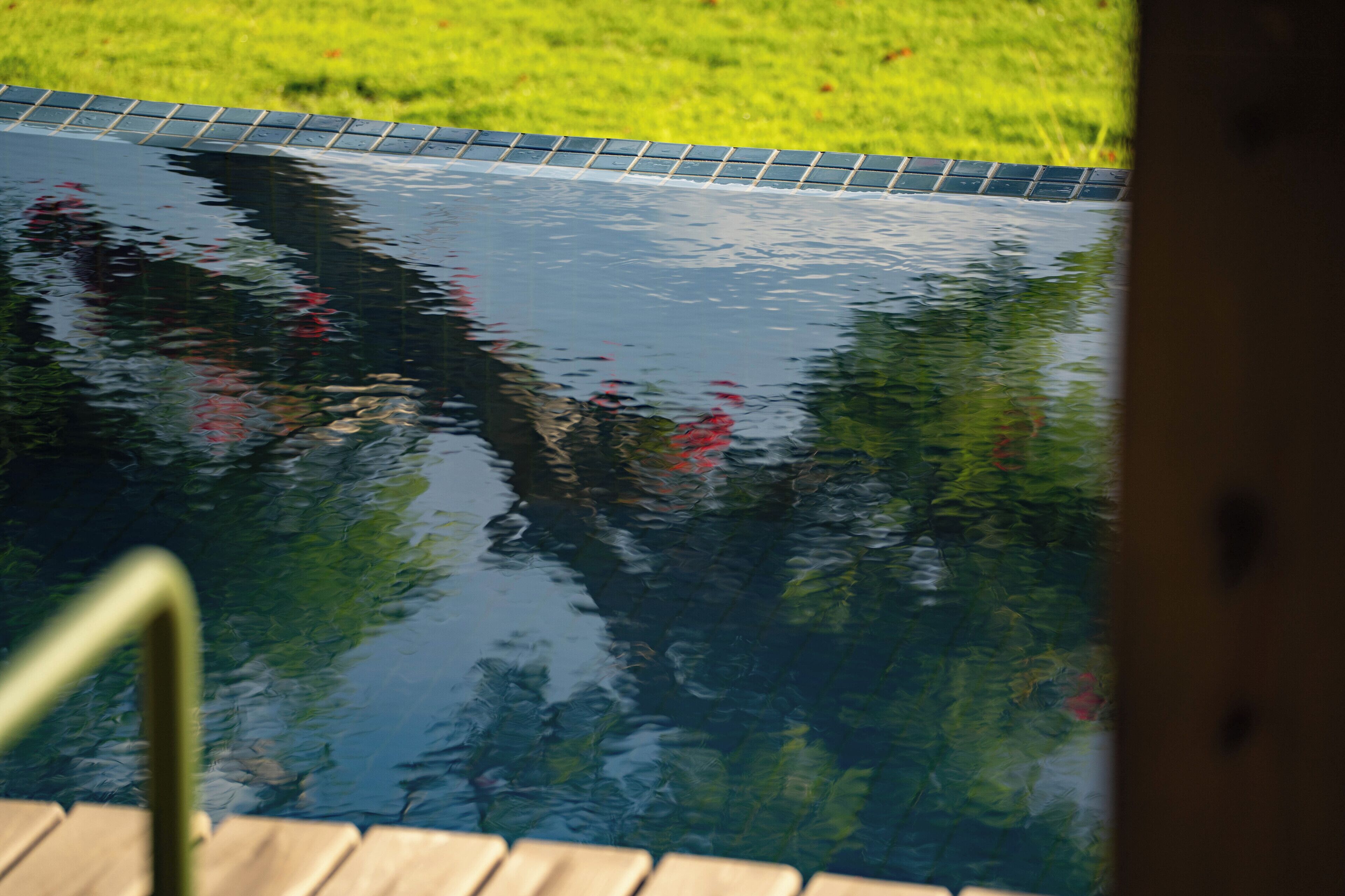 A swimming pool with a wooden deck and a tiled edge.