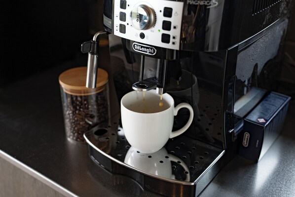 A coffee machine with a cup of coffee on a metallic tray. - Dei Amami (Amami)