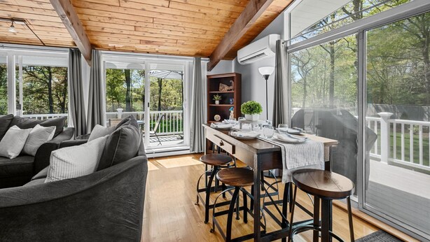 A cozy living room with a wooden ceiling, large windows, a sofa, and a dining area with stools. - Relax at This Dog-Friendly Sandwich Retreat (Sandwich)