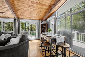 A cozy living room with a wooden ceiling, large windows, a sofa, and a dining area with stools. - Relax at This Dog-Friendly Sandwich Retreat (Sandwich)