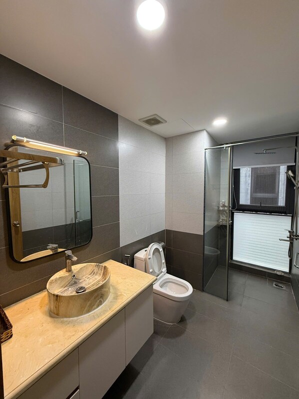 A modern bathroom with a vanity, sink, mirror, toilet, and glass shower enclosure.
