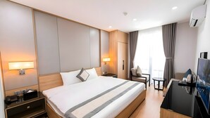 A modern hotel room with a large bed, bedside tables, a desk, and a TV. - Gloca Phu Quoc (Duong To)