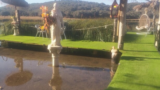 A statue on a platform with a grassy area and a water feature.