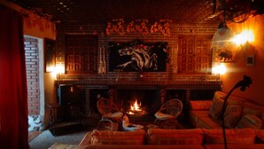 A cozy living room with a brick fireplace, two wicker chairs, and a sofa.
