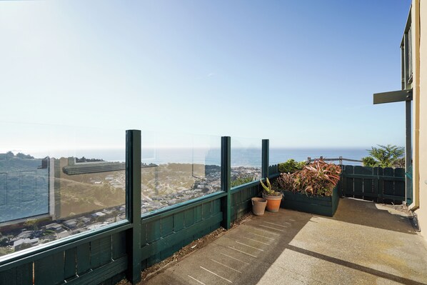 Un balcon offrant une vue sur le paysage urbain et l’océan.