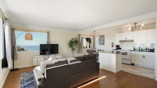 Un apartamento moderno con sala de estar, cocina y vista al océano.