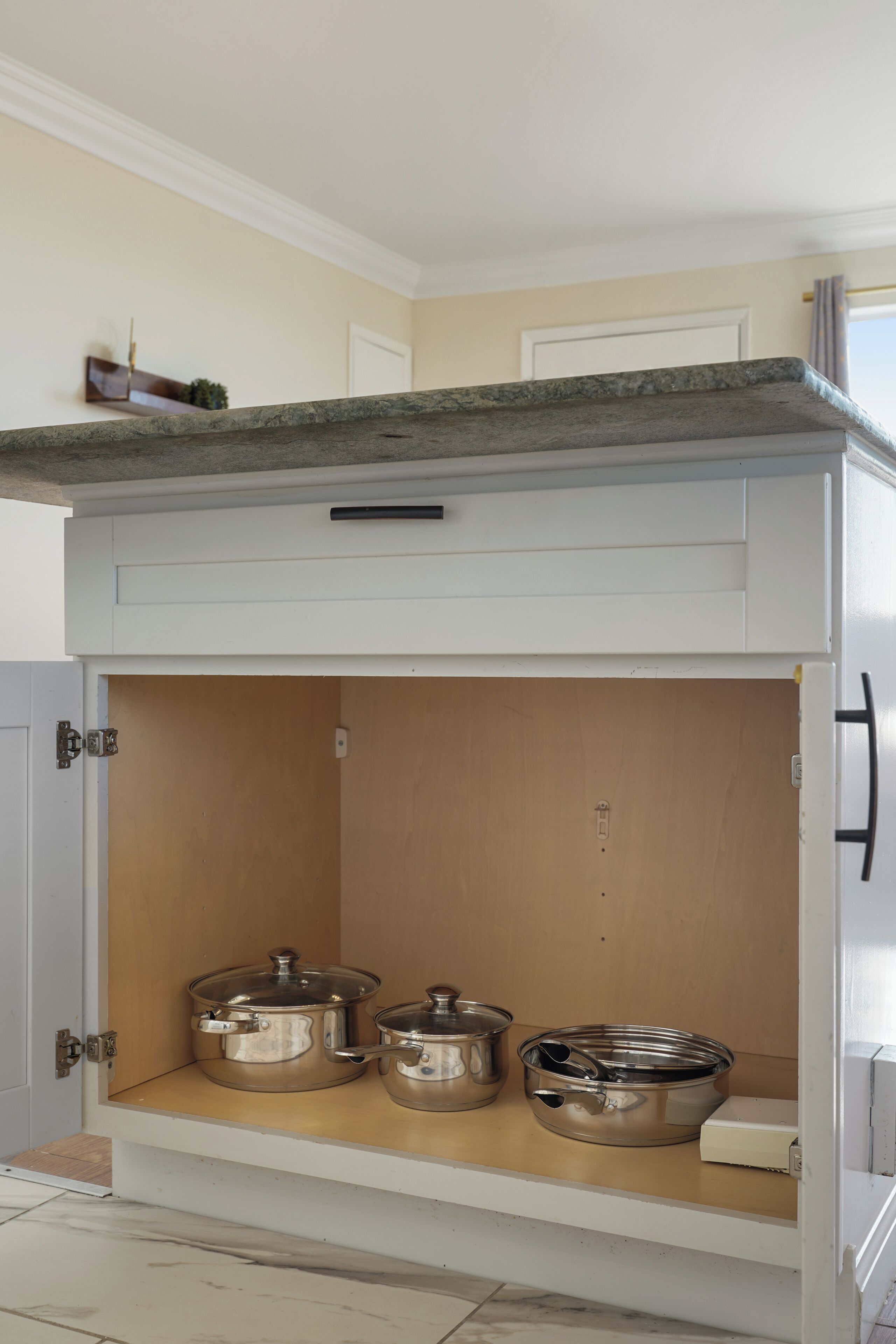 A kitchen with a built-in oven, a countertop, and a wooden cabinet below.