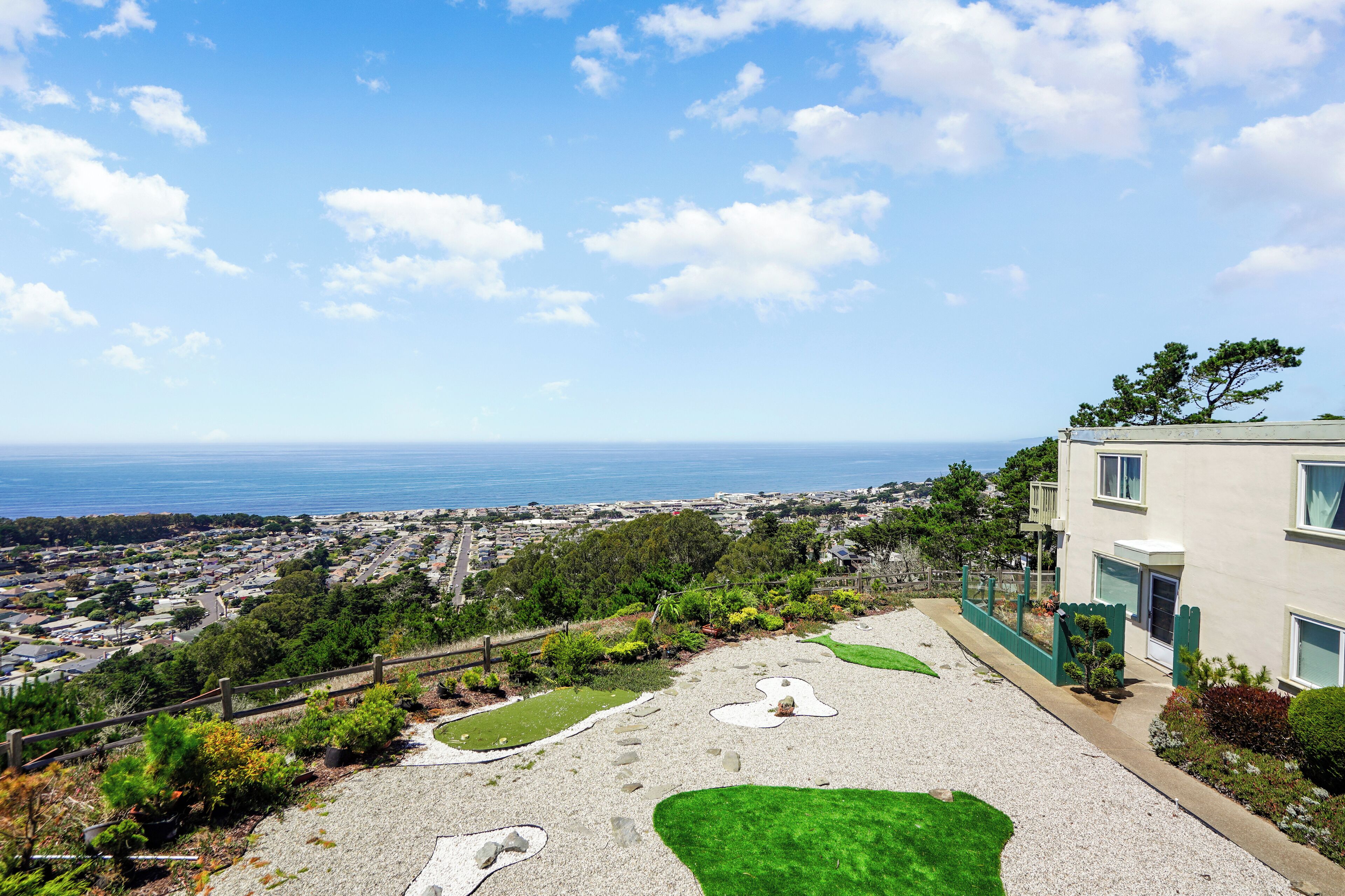 Una zona residenziale con vista sull'oceano, un vialetto lastricato e un edificio con un balcone.