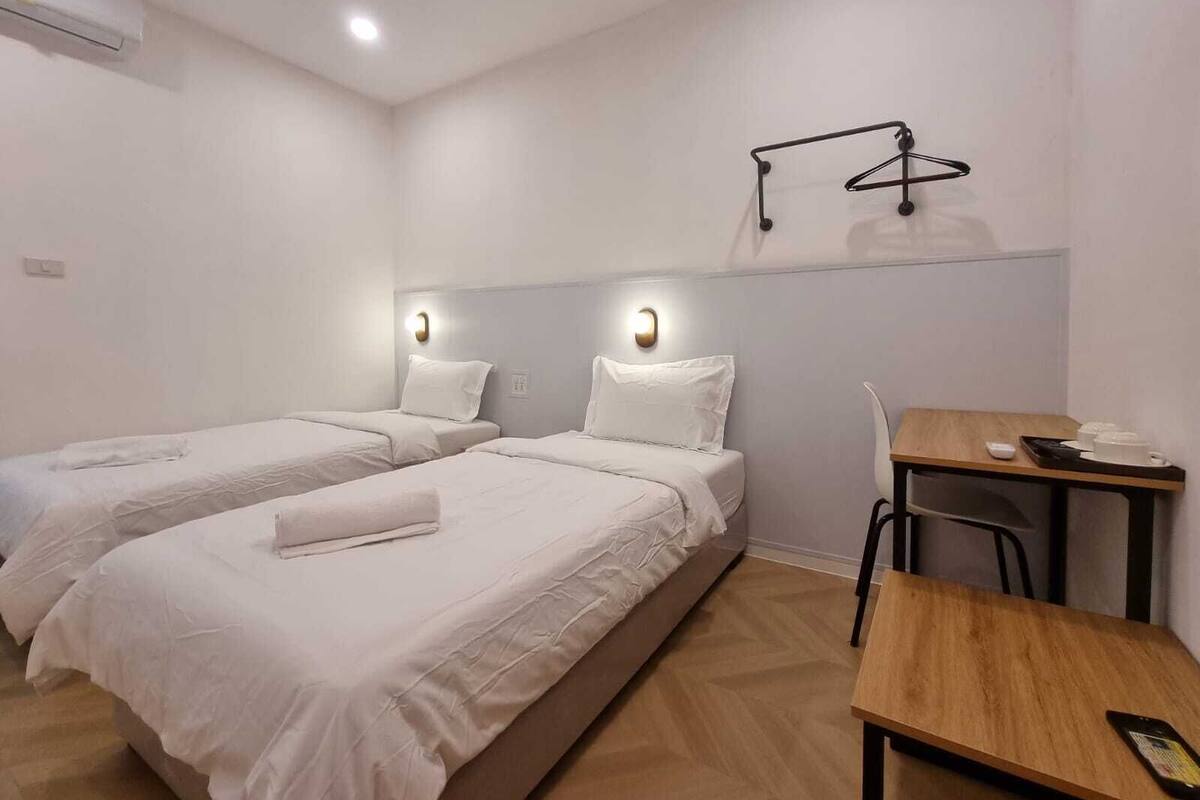 Une chambre d’hôtel avec deux lits, un bureau et une chaise.