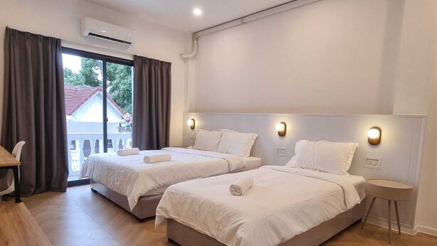 Habitación de hotel con dos camas, un escritorio y vista a un edificio.
